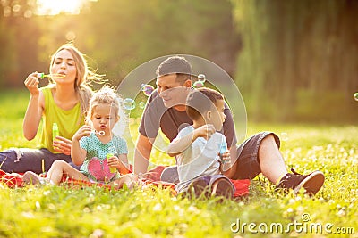 Happy family in the park together on a sunny day - children blow Stock Photo